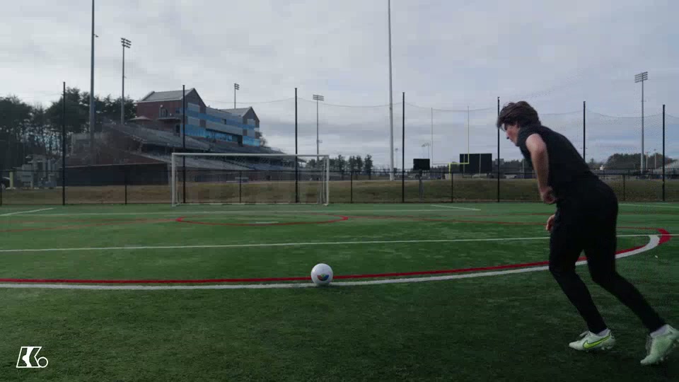Player stepping toward a stationary soccer ball on a training pitch, about to strike it.