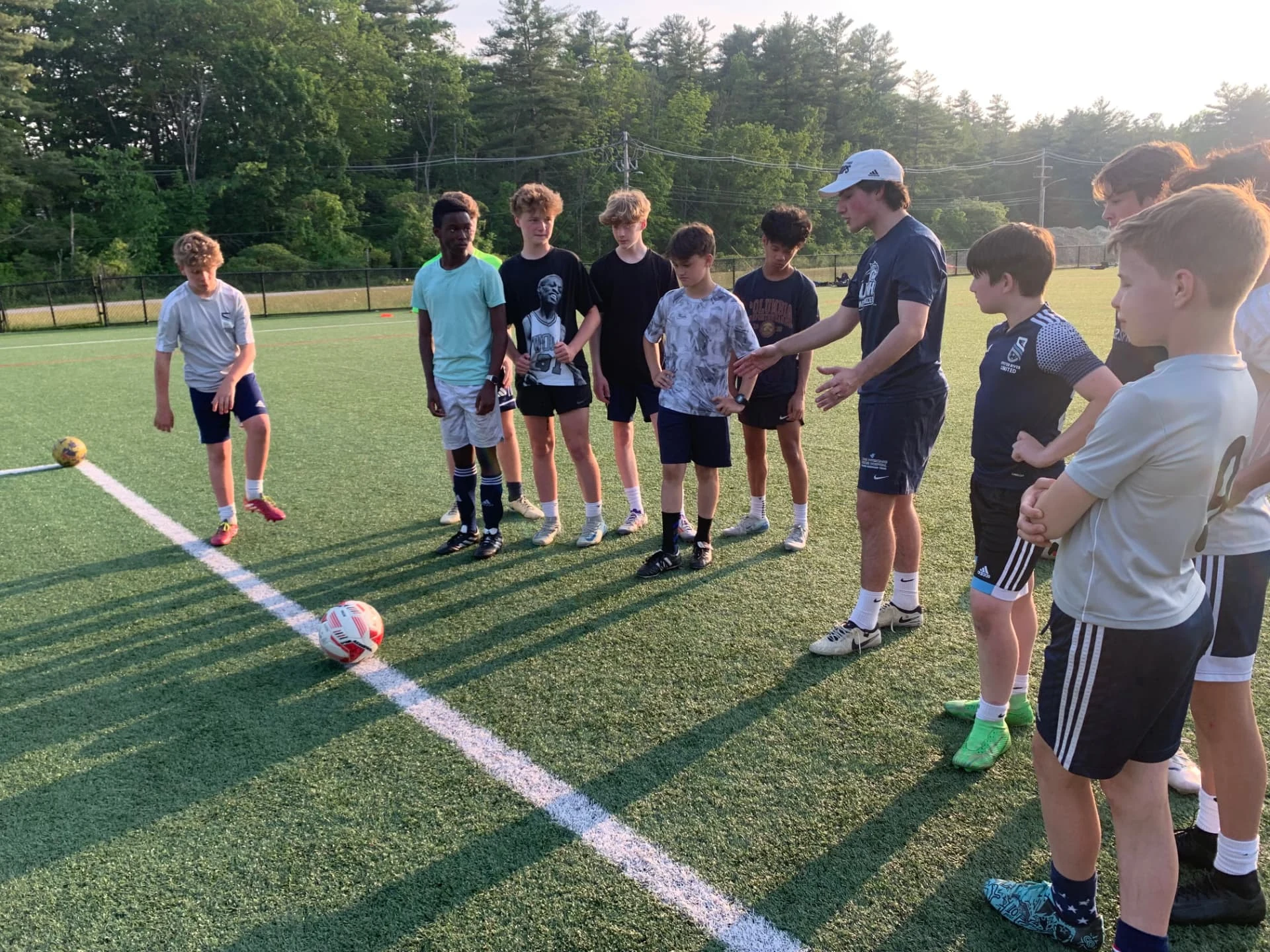 Adi Hicks demonstrating ball-striking technique to a group of teenage players.